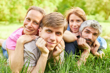 Two happy couples are lying in the grass on a meadow