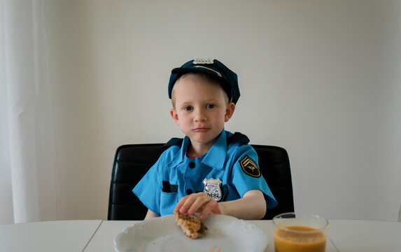 young boy in fancy dress as a police officer eating breakfast
