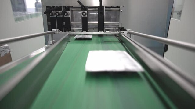 m&aacute;quina para la selecci&oacute;n de productos y envases de pl&aacute;stico rellenos de c&aacute;psulas y medicaci&oacute;n elaborada sobre cinta corredera verde por empresa de la industria farmac&eacute;utica.