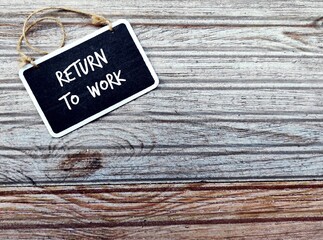 Chalkboard on wood copy space background with handwritten text RETURN TO WORK, process of bringing...