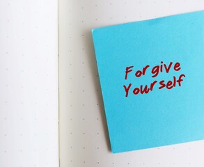 Blue note on white copy space background with handwritten text FORGIVE YOURSELF, concept of learning to fully accept whatever you did - let go any resentment you have made significant mistakes