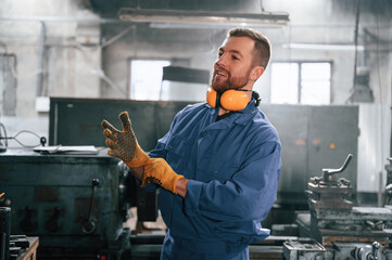 Working by using digital tablet. Man at the factory that is in blue uniform is indoors