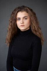 Fototapeta premium Front image portrait of a girl with curly hair, on a grey background.