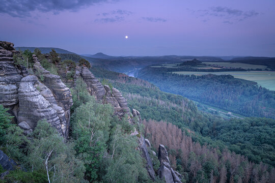Blick am Abend vom Schrammstein zum Sonnenuntergang im n&auml;chtlichen Mondlicht mit Massiv Gro&szlig;er Winterberg, Rosenberg und Zirkelstein, in &ouml;stliche bis ostwestliche Richtung in der S&auml;chsischen Schweiz.