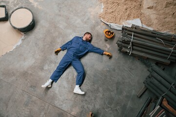 Top view of dead factory worker that lying on the ground. Conception of safety, bad accident