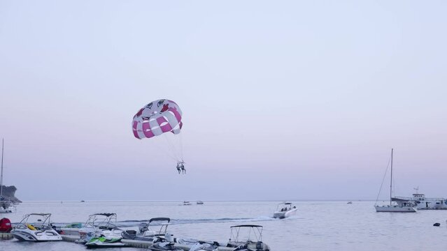 Couple parasailing at the sea, boat tows parachute