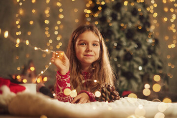 Cute little girl is lying down on the floor at home, celebrating New Year