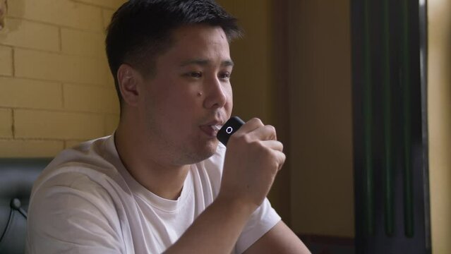Portrait of a man smoking a tobacco heating device at a table by the window in a cafe. Close-up of a sad guy smoking an electronic cigarette.