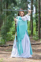 Young beautiful Asian woman dressed in ancient Chinese warrior style with ancient fan. cute girl in green dress