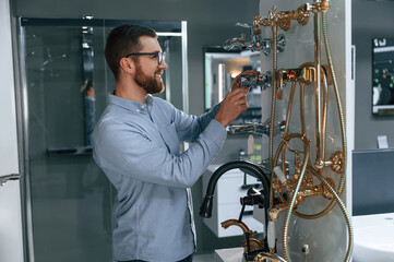 Selects a shower faucet. Man chooses a products in a sanitary ware store