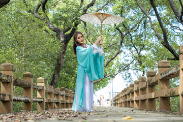 Obraz premium Young beautiful Asian woman dressed in ancient Chinese warrior style with ancient fan. cute girl in green dress 