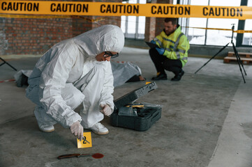Naklejka na ściany i meble Knife as evidence. Blood is on the floor. Detectives are in a crime scene near dead body