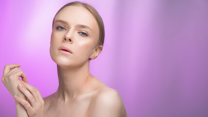 Obraz na płótnie Canvas Beauty and skin care. Happy woman with fresh radiant, moisturized skin, standing with bare shoulders, with light makeup and natural skin on a pink background.