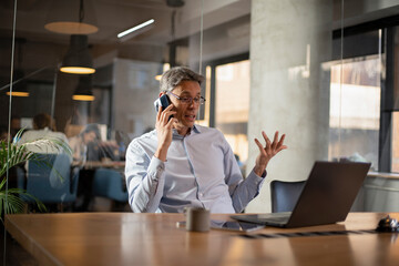 Businessman in office. Handsome man talking on phone at work.