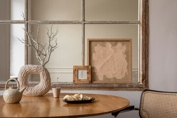 Creative composition of dining room interior with mock up poster frame, round table, rattan chair,...