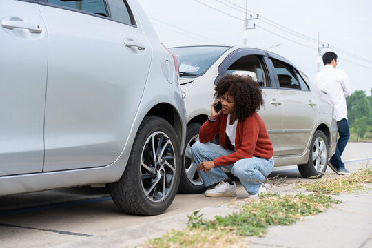 Asian women driver check for damage after a car accident before taking pictures and sending insurance. Online car accident insurance claim after submitting photos and evidence to an insurance company.