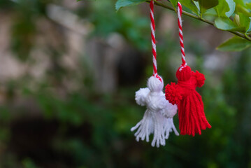 Traditional Martisor on green tree branch - symbol of 1 March, Martenitsa, Baba Marta, beginning of spring and seasons changing in Romania, Bulgaria, Moldova. Greeting and post card for holidays.