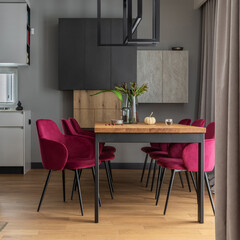Stylish composition of elegant dining room interior design with velvet chairs, design wooden table, lamps, chimney and beautiful personal accessories. Modern home decor. Template.