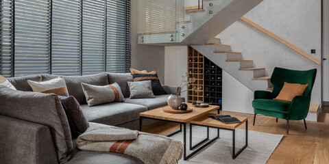 Stylish composition of living room interior with corner grey sofa, green velvet armchair, coffee...