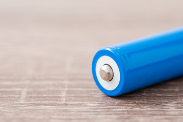 Close-up shot of 18650 battery on wooden table. New fully charged battery, positive polarity side
