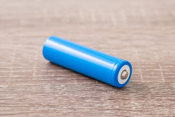 Blue li-ion battery on wooden table. New 18650 battery with 3.7 voltage