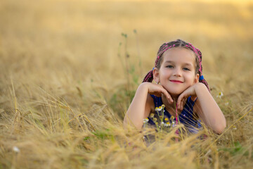 A six-year-old girl lies in a wheat field.