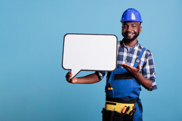 Smiling construction worker pointing to blank dialogue cloud with copy space, advertising mockup....
