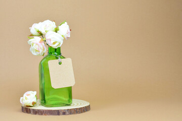 Glass container with a small bouquet of fabric roses, decorative. Light brown background and copy space.