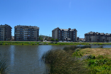 Fototapeta na wymiar a river and some green areas near an urbanization of buildings and houses