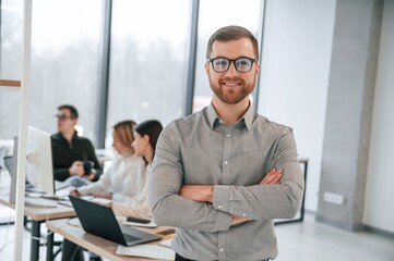 Obraz premium Man is standing with arms crossed. Successful team are working together in the office. Conception of business