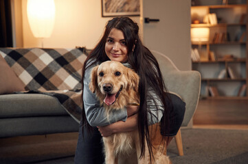 Portrait of woman that is with golden retriever dog at home