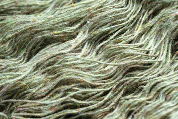 Threads of natural organic sheep wool. Unwound skein of olive green knitting yarn.