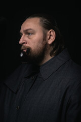 Fototapeta premium stylish man in retro outfit suit hat smoking wooden pipe sherlock holmes look cosplay england gentleman fashionable confident gangster Guy Ritchie Charlie Hunnam style
