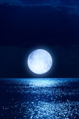 Naklejka na ściany i meble Full Moon with starry skies rising above ocean horizon.