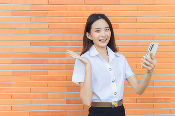 Portrait of beautiful an Asian Thai girl student in uniform is standing smiling happily and...