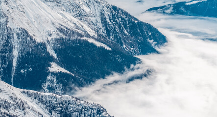 Clouds cover the mountains with snow in winter