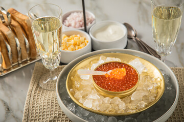 Orange Keta Lachs Kaviar in Dose auf Eis in Glas Schale mit Perlmutt Löffel, Sekt Champagner,...