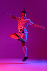 Fototapeta na wymiar Young professional female football, soccer player in motion, training, playing over gradient pink background in neon light