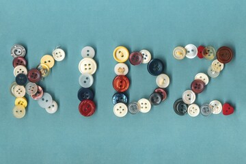 Kids, colorful button badges, text over blue background. Collection of assorted spare clothes buttons vintage. Sewing tools close up framing fabric background.