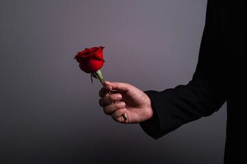 man hand wearing suite with red rose flower on background. holidays card with copy space valentine...
