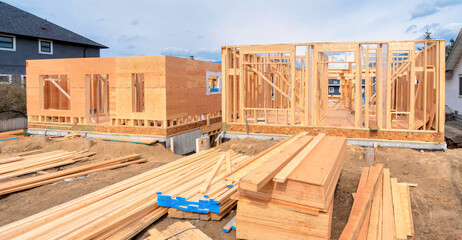 Wooden frame of two new houses with engineered lumber materials in front - obrazy, fototapety, plakaty