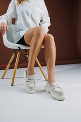 Women shoes. Close up of female legs in leather white loafers. New spring-summer collection of...