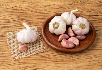 Garlic bulb and cloves on a plate over wooden table