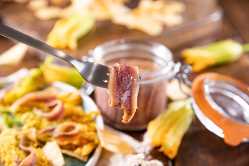 Anchovies in a jar, on a wooden rustic background. Traditional italian food of the south of italy and sardinia. Anchovy Fillets. small but herring. 