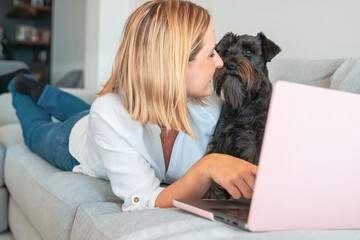 Happy Young Beautiful Woman Using Laptop with her dog, Indoors