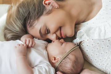 Baby girl and her beautiful young mother in a cozy house, light pastel colors. Newborn. Motherhood....