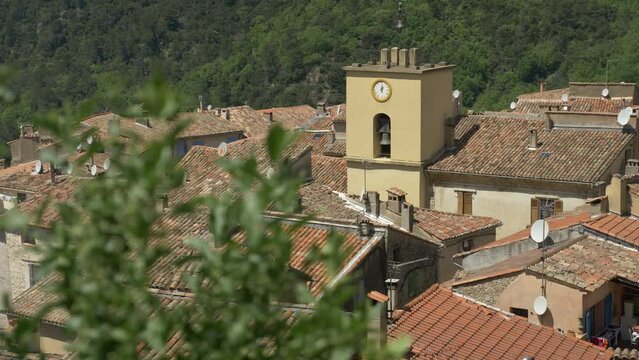 Clocher vu de loin atour de pleins de toits de maisons et b&acirc;timents, et de la v&eacute;g&eacute;tation en arri&egrave;re plan 