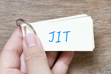 Hand hold flash card with handwriting in word JIT (abbreviation of just in time) on wood background