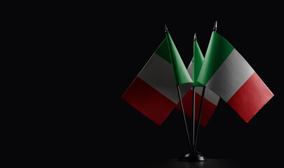 Small national flags of the Italy on a black background