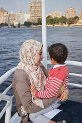 Happy mother with adorable son resting on a big yacht sailing in Nile, Cairo, Egypt. 